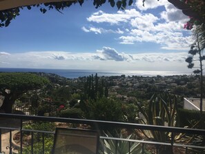 Ein Balkon mit Blick auf eine Küstenstadt, darunter Häuser und ein Gewässer.
