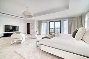Ein modernes Schlafzimmer mit einem großen Bett, einem Fernseher und Blick auf die Stadt.