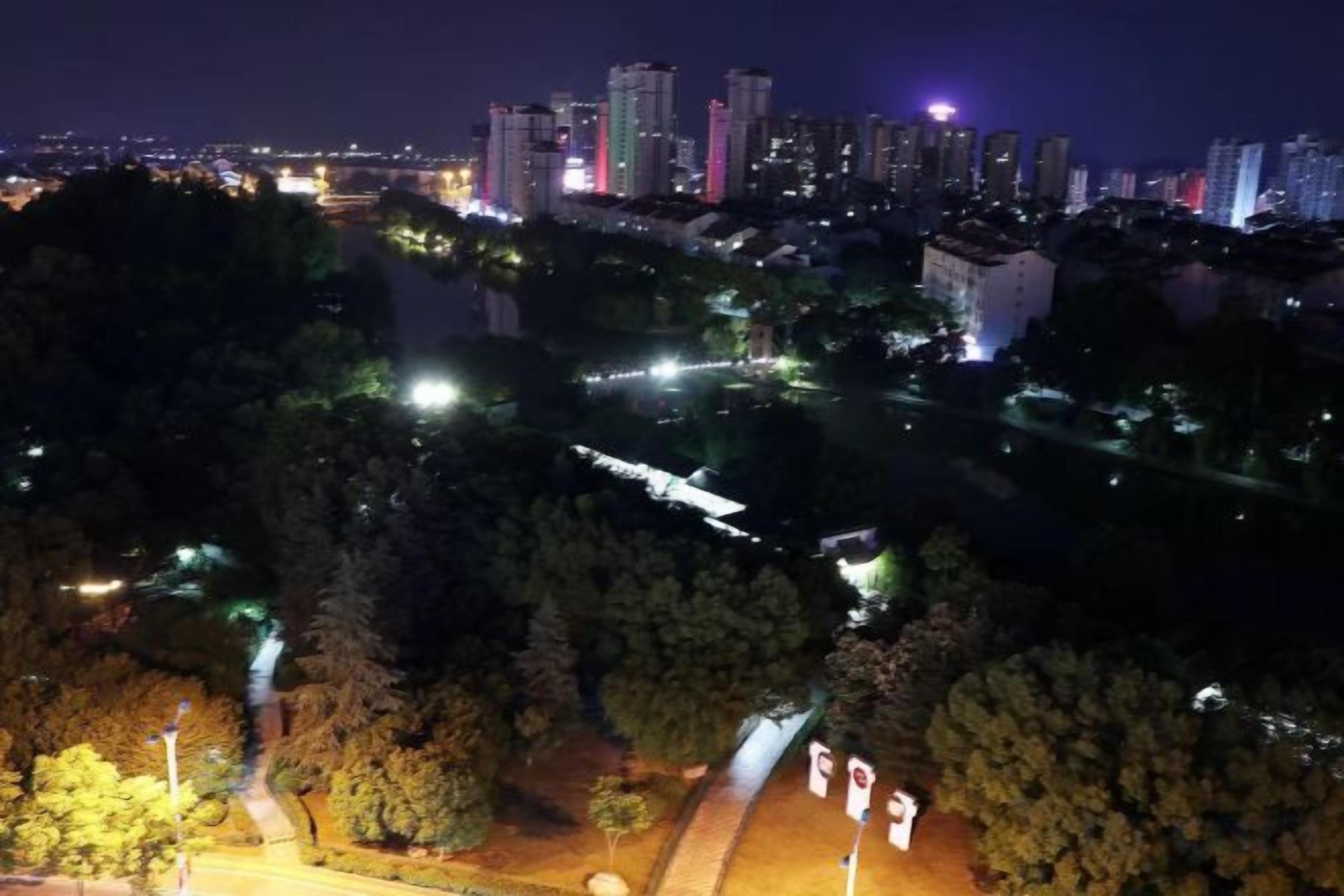 A nighttime cityscape with illuminated buildings and a river.