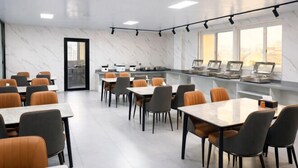 A modern conference room with marble walls, multiple tables, and chairs, equipped with presentation screens. - Carnival Hotel (Chizhou)