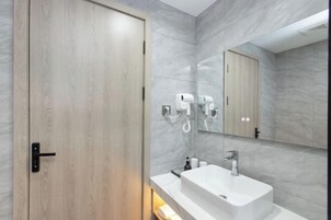 Un baño moderno con puerta de madera, lavamanos blanco y espejo.