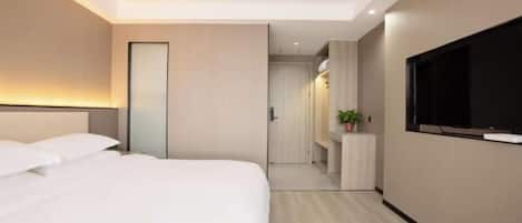 A modern hotel room with a large bed, a TV mounted on the wall, and a small desk area.