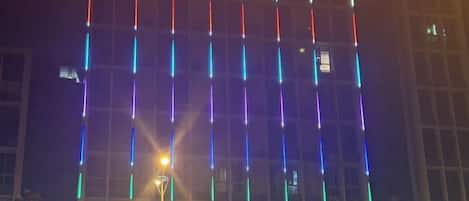 Une façade d’immeuble ornée de bandes lumineuses verticales.