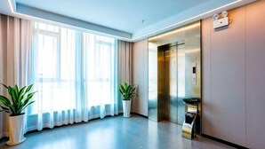 A modern hotel lobby with a large window, a reception desk, and an elevator. - Carnival Hotel (Chizhou)