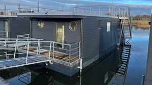 A stationary boat with a covered deck, a staircase, and a small window.