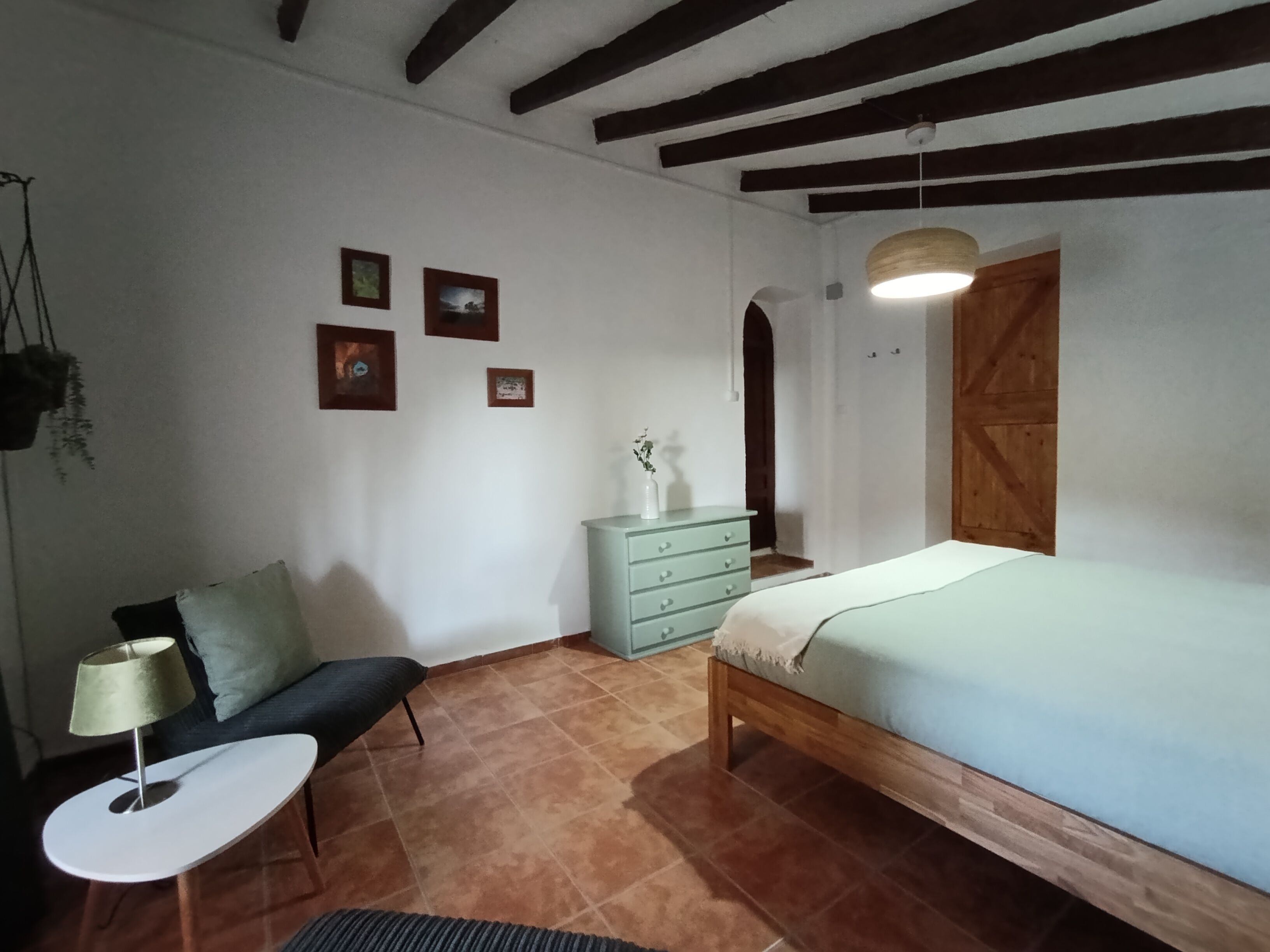 Un dormitorio con cama, cómoda, silla y una pequeña mesa.