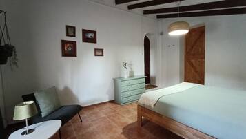 Un dormitorio con cama, cómoda, silla y una pequeña mesa.