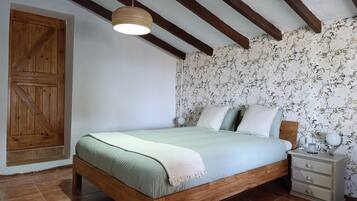 A bedroom with a wooden bed, a nightstand, a hanging light fixture, and a wooden wardrobe.