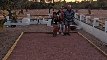 Grupo de personas de pie alrededor de una mesa de billar en un espacio exterior.