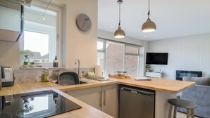 Une cuisine moderne dotée d’un plan de travail en bois, d’un lave-vaisselle encastré et d’une grande fenêtre.