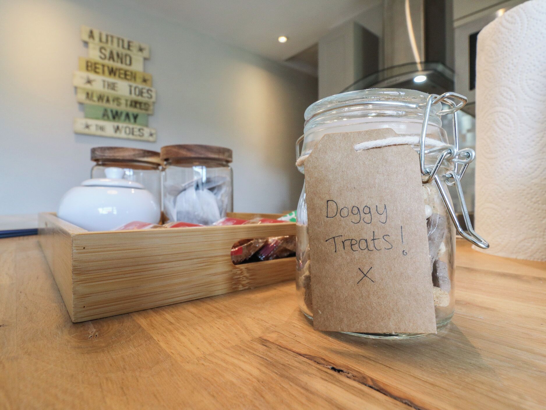 A wooden table with a glass jar labeled "Doggy Treats!" and a wooden box with jars.