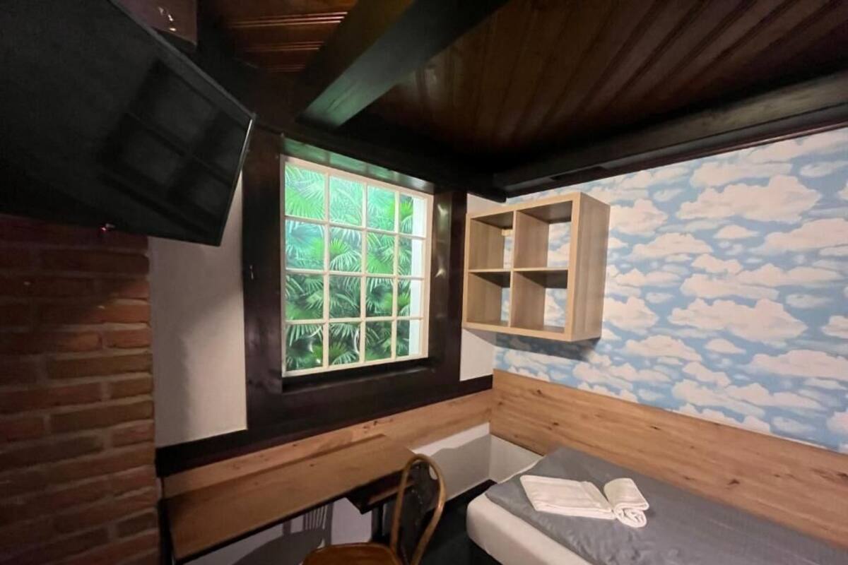 A compact room with a bunk bed, a small desk, a chair, and a window with a view of palm trees.