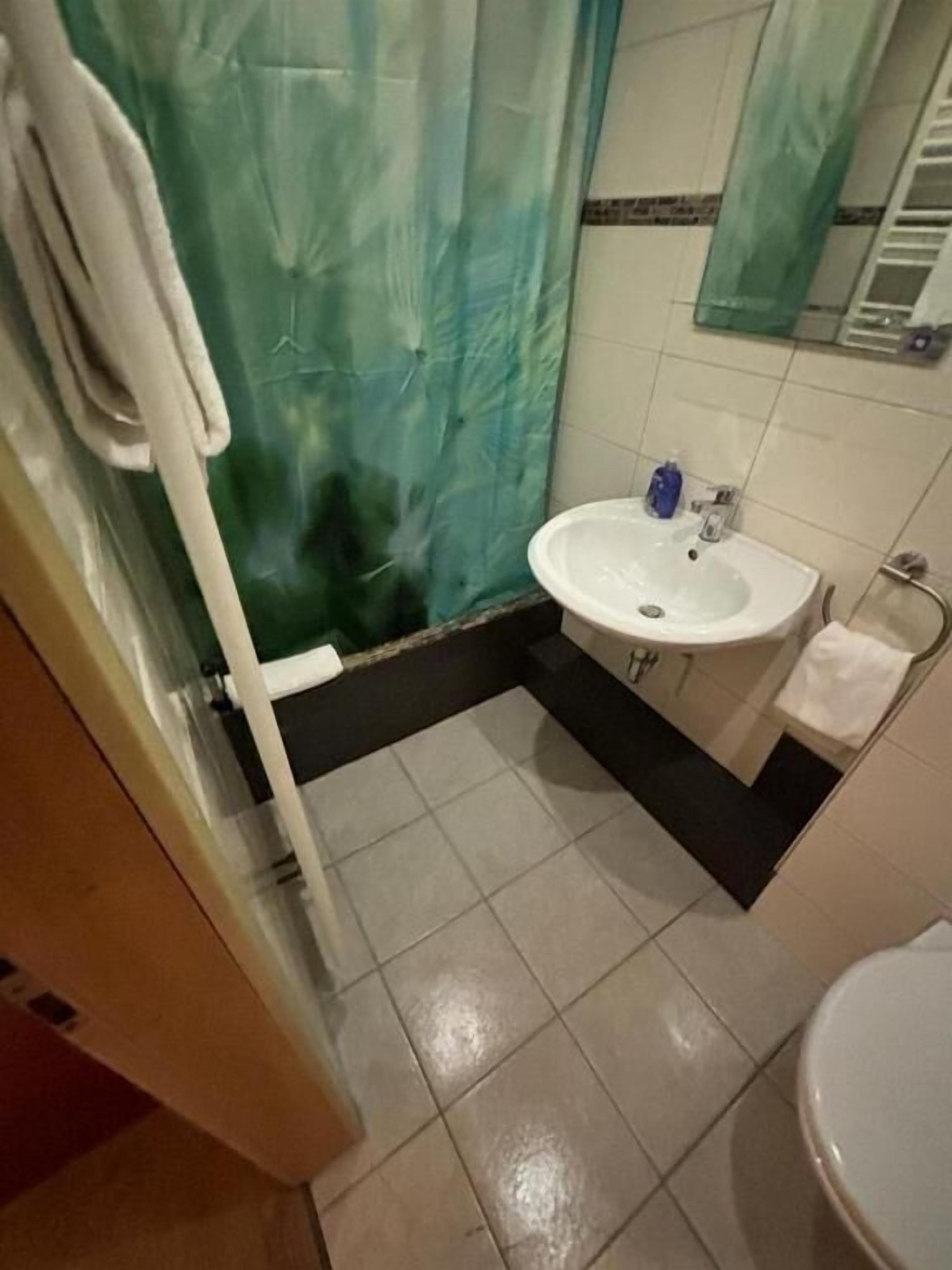 A bathroom with a white sink, a mirror, and a toilet.