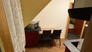 Une petite cuisine équipée d’un four à micro-ondes, une table à manger avec deux chaises et un plancher en bois.