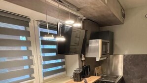 Une cuisine compacte dotée d’un plan de travail en bois, d’un four à micro-ondes, d’un évier et de deux tabourets de bar.
