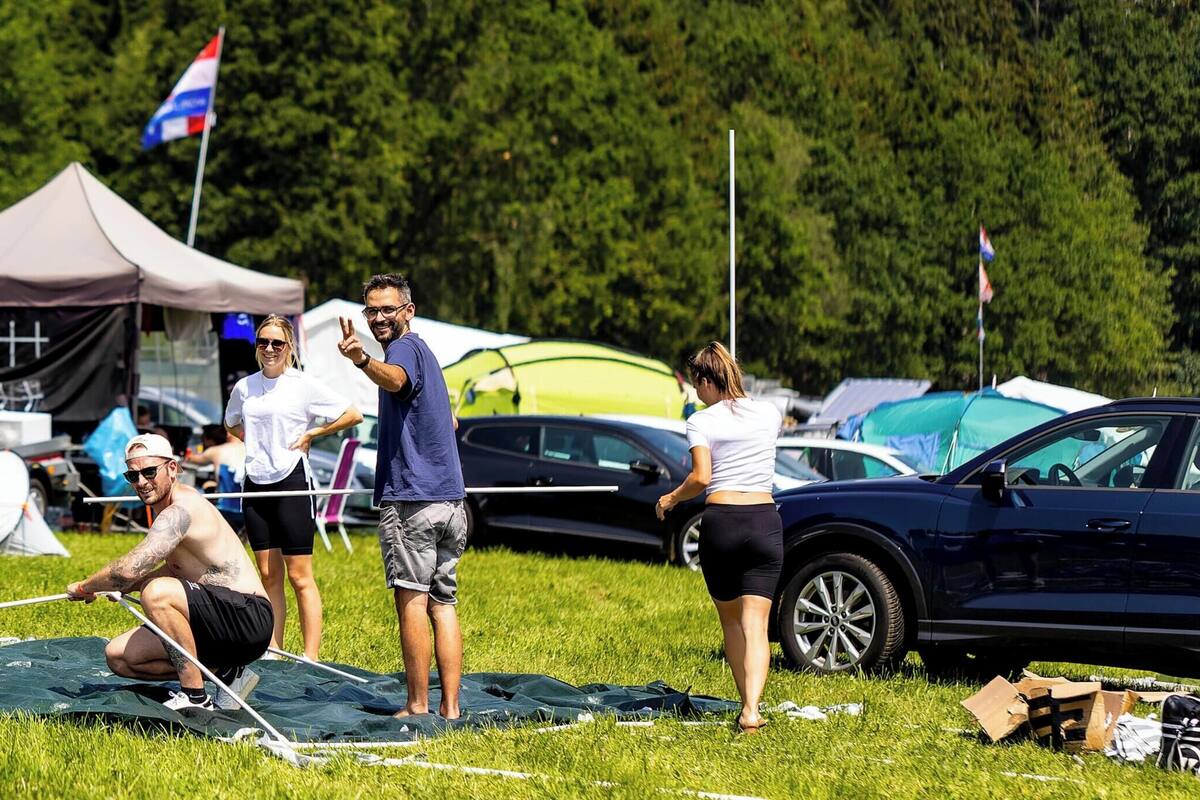 Un camping con tiendas de campaña, una caravana y personas realizando actividades.