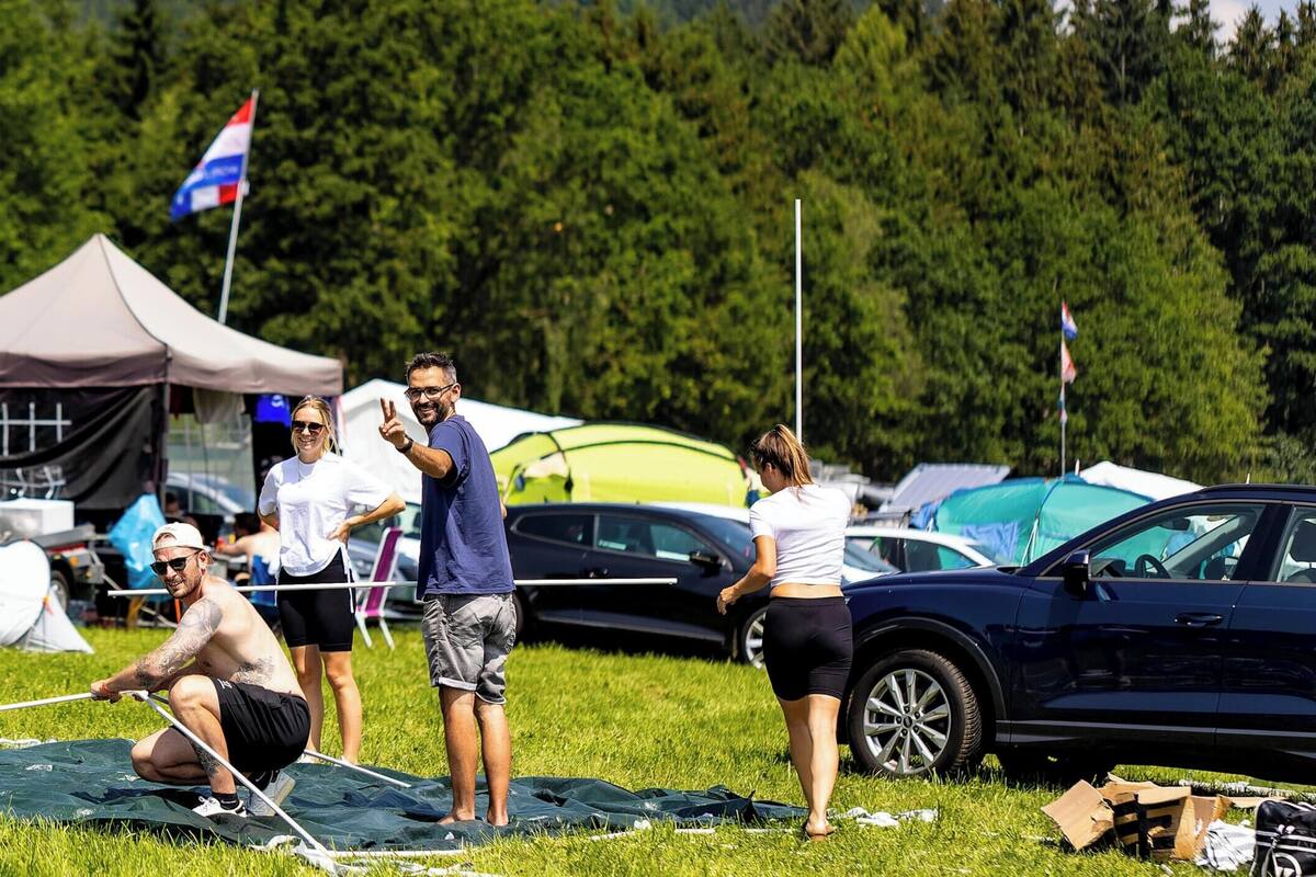 Un campamento con tiendas de campaña, una caravana y gente realizando actividades.
