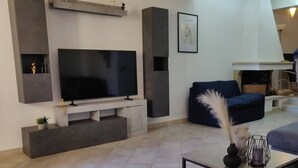 A modern living room with a large flat-screen TV, built-in shelving, a blue sofa, and a coffee table with decorative items.