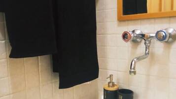 Un bagno con un lavandino bianco, uno specchio sopra e un portascopevoli con un asciugamano nero.
