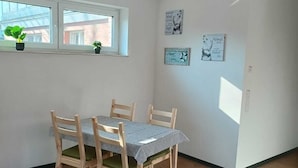 A dining area with a table and chairs, a window with plants, and wall decorations. - Aurich's heart: pure pub flair (Aurich)