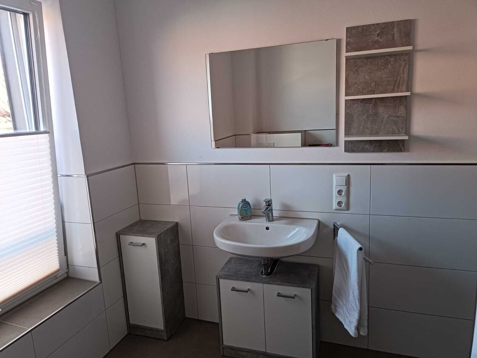 Ein modernes Badezimmer mit Waschbecken, Spiegel und Handtuchhalter.