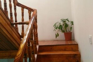 Un escalier en bois, doté d’une rampe et agrémenté d’une plante en pot sur le palier.