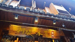 A traditional wooden building with a signboard and a tiled roof. - Fengyuanju Inn (Fenghuang County)