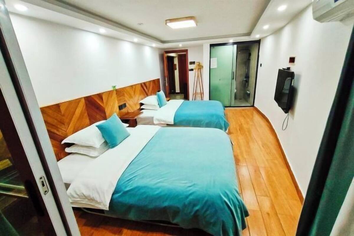 A hotel room with two beds, a wooden headboard, a flat-screen TV, and a wooden floor.