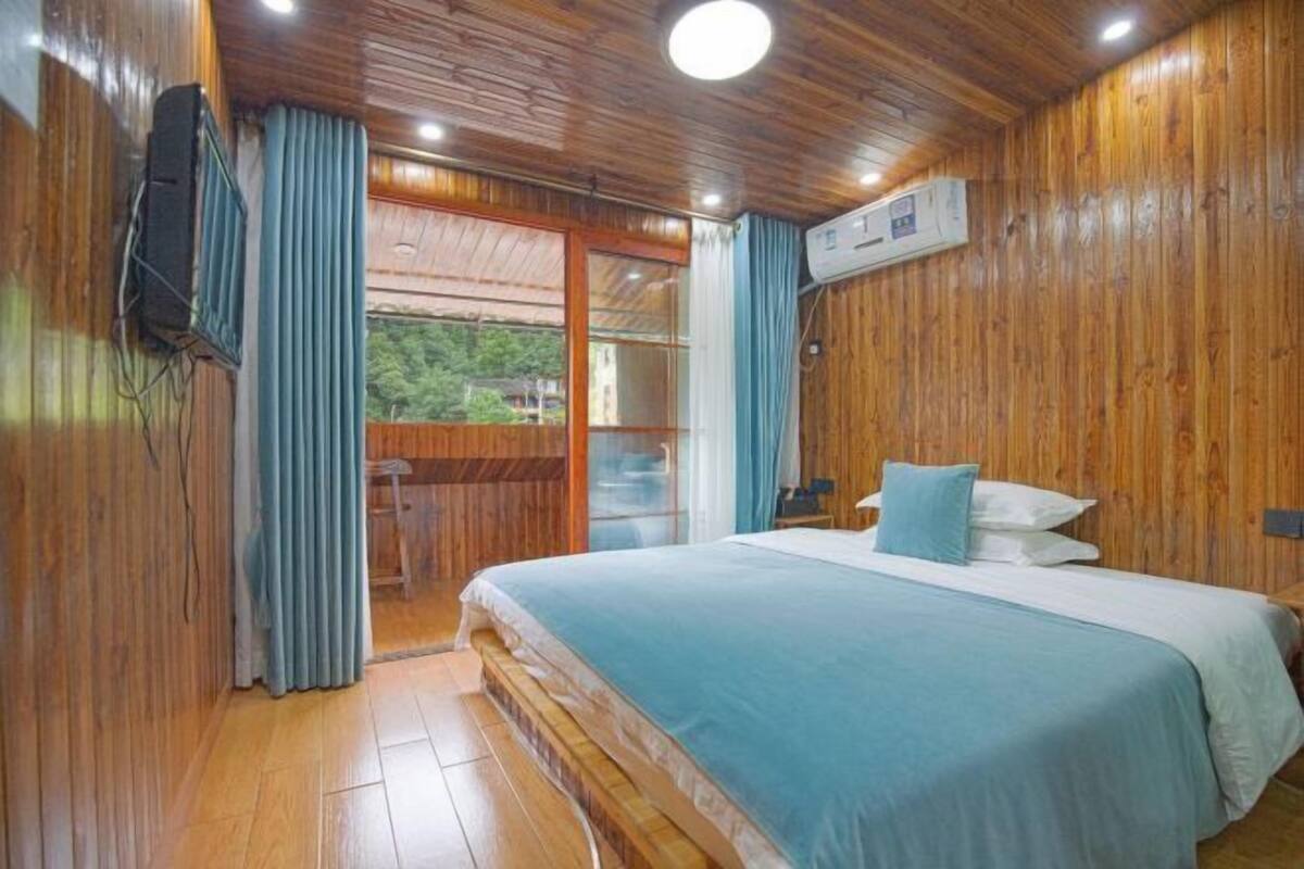 A wooden-paneled room with a bed, curtains, and an air conditioning unit.