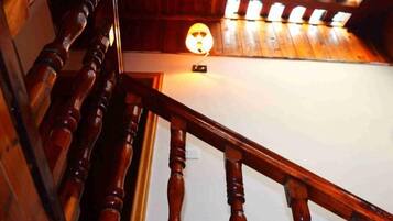 A wooden staircase with a handrail and a light fixture on the wall.