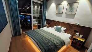 A modern hotel room with a large bed, a nightstand, a wall-mounted TV, and a sliding door leading to a bar area. - Fengyuanju Inn (Fenghuang County)