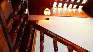 A wooden staircase with a handrail and a light fixture on the wall. - Fengyuanju Inn (Fenghuang County)