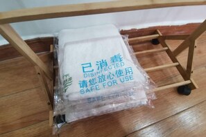 A wooden chair with wheels and a plastic bag containing a white cloth with text. - Fengyuanju Inn (Fenghuang County)