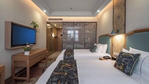 Habitación de hotel con dos camas, un televisor, un escritorio y un cuadro grande en la pared.