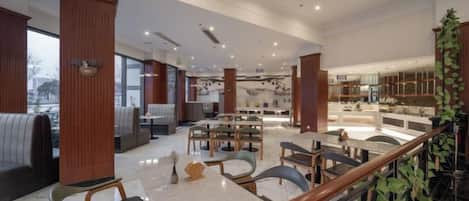 A spacious hotel lobby with seating areas, a staircase, and a view of the city.