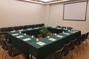 A conference room with a long table, chairs, nameplates, and a projector screen. - Grand Cozy Hotel (Yangzhou Dongguan Street) (Yangzhou)