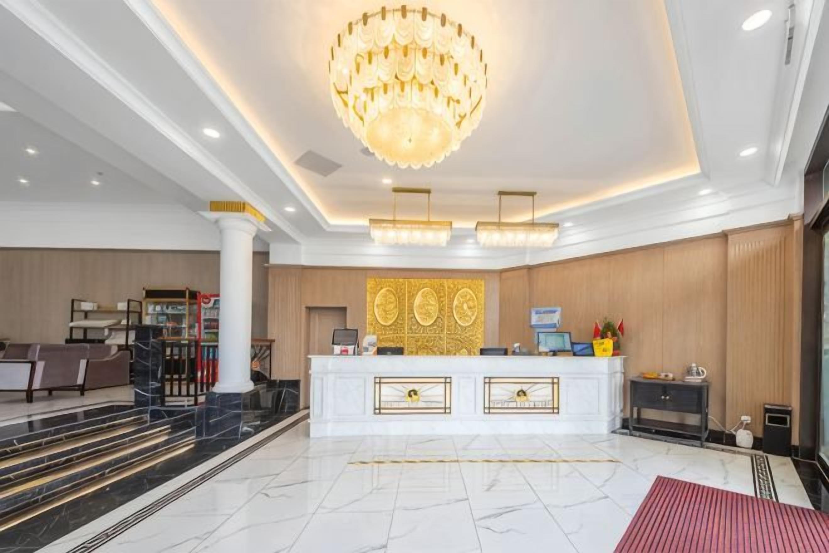 Un vestíbulo de hotel con una recepción, una araña y una zona de estar.