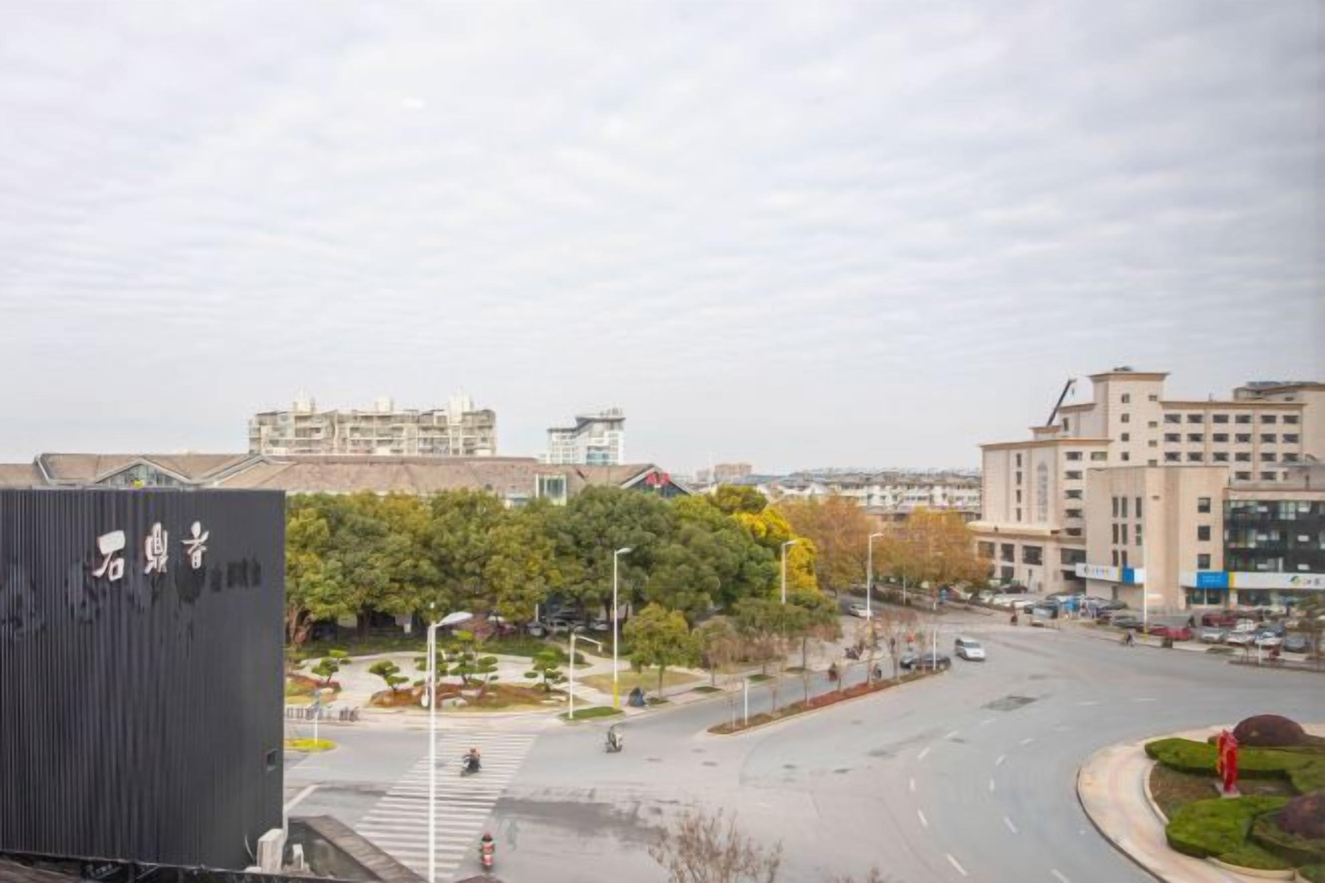 A cityscape with a modern building, a roundabout, and a distant view of other buildings.