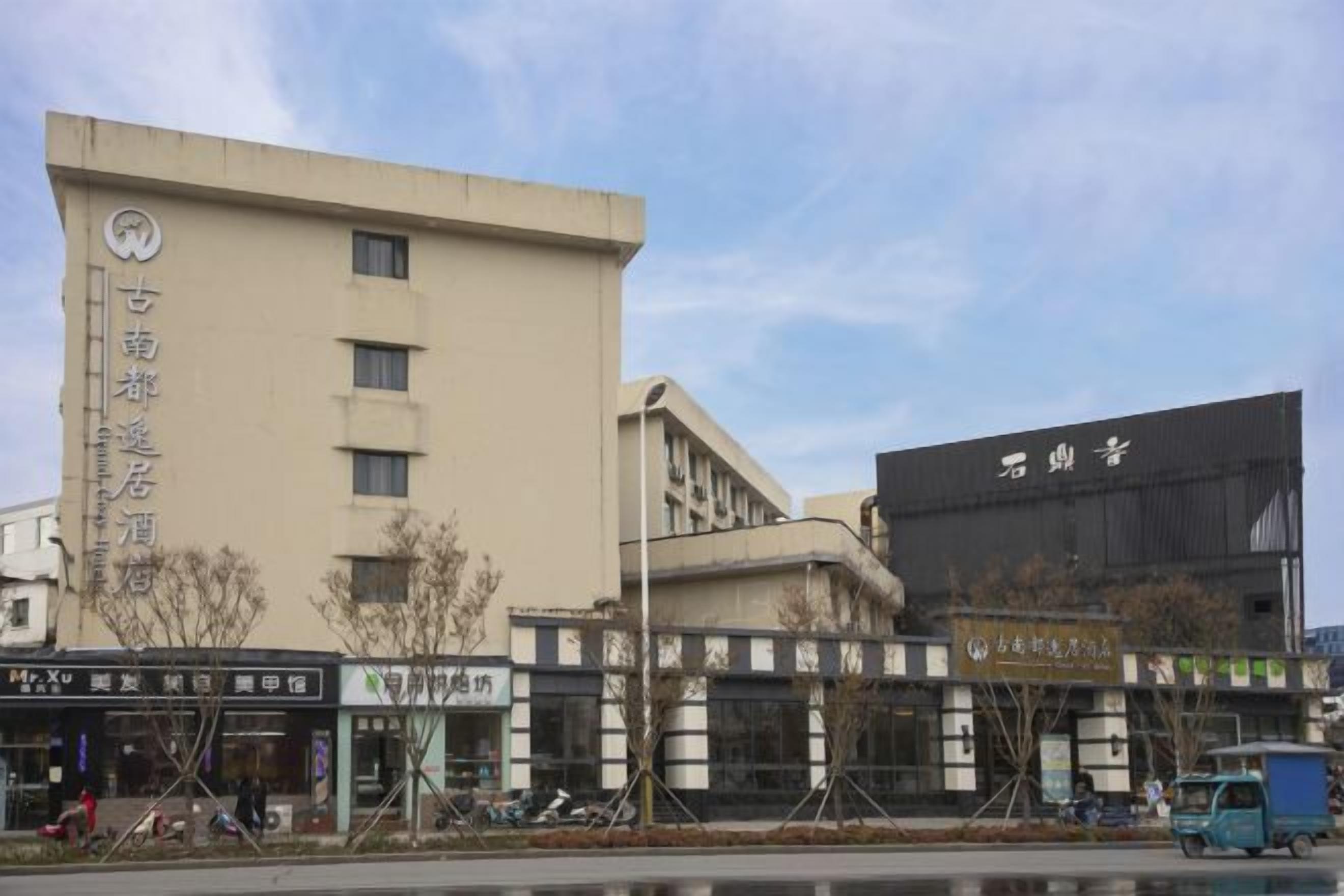 Un edificio de varios pisos con letreros que indican que es un hotel. Hay locales comerciales con letreros en la parte frontal del hotel.