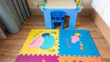 Quarto com mesa azul e tapete colorido com personagens de animais.