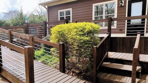 Una terraza de madera que lleva a una casa con un felpudo que dice 'hello'.