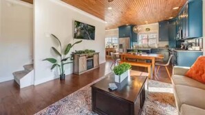 Amplia sala de estar con techo de madera, una mesa de comedor y una cocina al fondo.