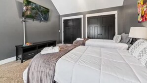 Un dormitorio con dos camas, un televisor, un banco y una puerta que da a un armario.