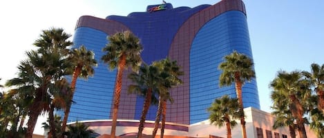 A large, modern hotel with a curved facade and a prominent logo at the top.