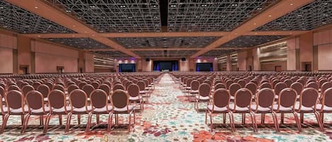 A large conference room with rows of chairs, a patterned carpet, and a high ceiling with a grid-like structure.