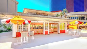 Un ristorante con posti a sedere all'aperto e un tetto di paglia.