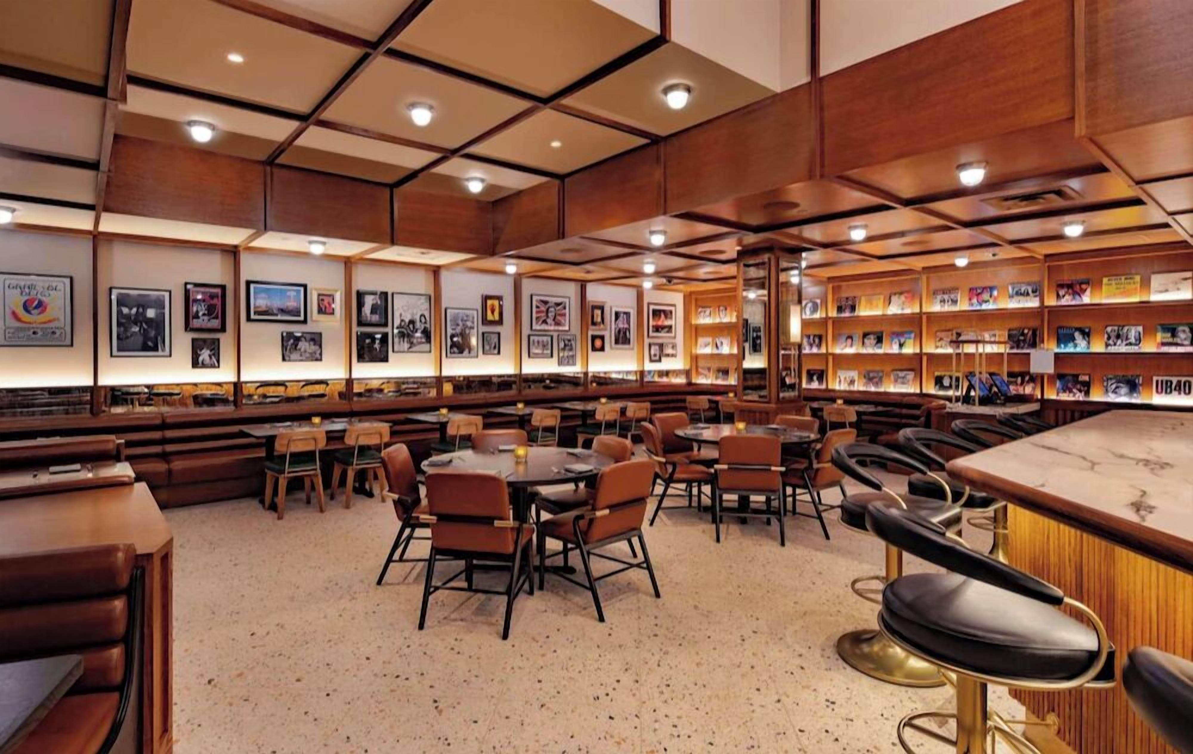 Un restaurante con cabinas y mesas, paneles de madera y cuadros en las paredes.