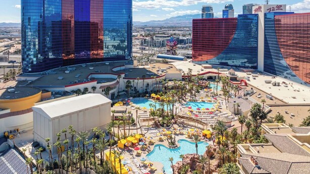 A hotel with a large pool area, multiple buildings, and a desert landscape in the background. - Masquerade Tower at Rio Hotel & Casino (Las Vegas)