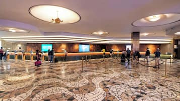 A lobby with a reception desk, a large chandelier, and a mosaic floor.