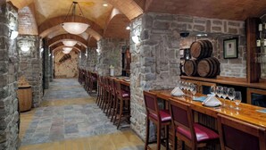 A stone-walled dining area with wooden tables and chairs, a long corridor, and barrels on the wall. - Masquerade Tower at Rio Hotel & Casino (Las Vegas)